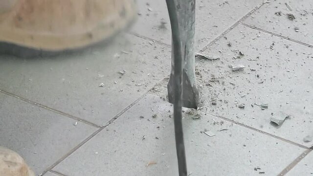 close up of a worker with demolition jackhammer breaking floor in on building site. House industry with men at work with an electric pneumatic hammer. Working process dismantling a floor. SLOW MOTION