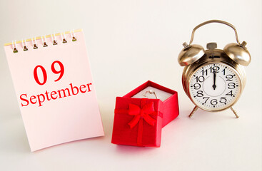 calendar date on light background with red gift box with ring and alarm clock with copy space....