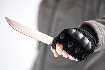 A gloved robber holds a knife threateningly. The concept of self-defense against bullies.