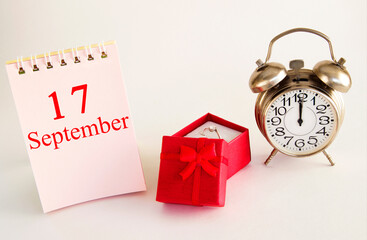 calendar date on light background with red gift box with ring and alarm clock with copy space. ...
