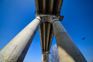 bottom view of man jumping from high bridge on sky background at sunny day 