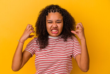 Young african american woman isolated on yellow background upset screaming with tense hands.