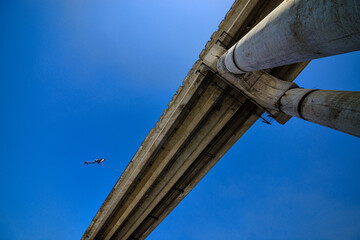 bottom view of man jumping from high bridge on sky background at sunny day 