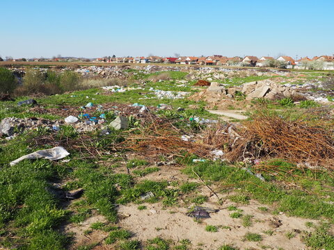 garbage dump near the village. Chaotic unofficial dump. Plastic, bags, paper, glass, biological waste. Green grass next to dirt. Ecological catastrophy. Sremska Mitrovica, Chalma, Serbia, 5 April 2021