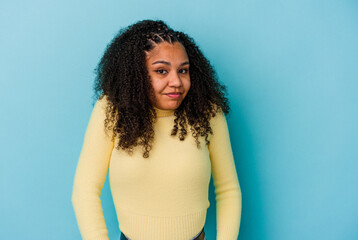 Young african american woman isolated on blue background shrugs shoulders and open eyes confused.