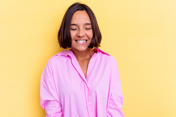 Fototapeta premium Young mixed race woman isolated on yellow background laughs and closes eyes, feels relaxed and happy.