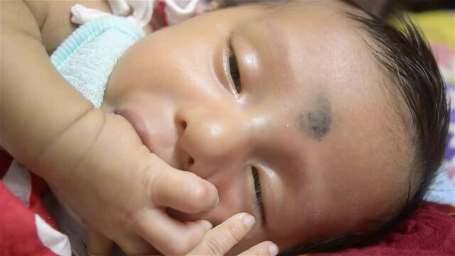 Cute Newborn hungry baby thumb sucking in sleeping. Funny baby video footage. Close up portrait of cute Sweet infant toddler sleeping in drowsy eyes with sleepy mood. Child care peace background.