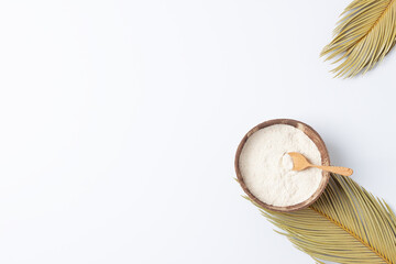Collagen powder in bowl with measure spoon with palm leaves on white background. Flat lay, copy...