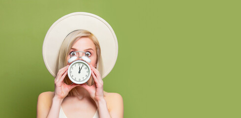 Beautiful blonde girl in white hat and dress with alarm clock