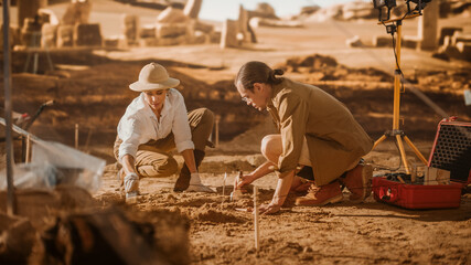 Archaeological Digging Site: Two Great Archeologists Work on Excavation Site, Carefully Cleaning with Brushes and Tools Newly Discovered Ancient Civilization Cultural Artifact, Fossil Remains - obrazy, fototapety, plakaty