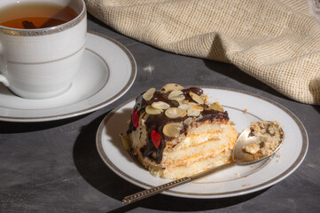 Still life - layered homemade sponge cake and a cup of black tea in a white dish, and a linen...