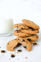 Homemade chocolate chip cookies and glass of milk on marble background. Recipe of oatmeal cookies with chocolate chips. Variant of morning breakfast.
