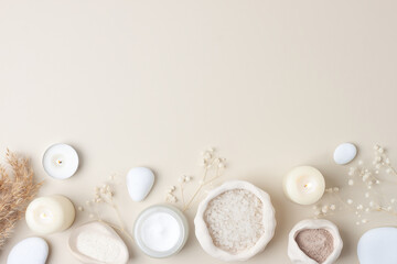 Spa composition with skin care products, stones, candles and flowers on pastel beige. Flat lay