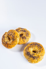 Freshly made and baked bagels on white background. Homemade cooking and pastry concept. Vertical photo and selective focus