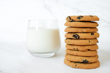 Stack of homemade chocolate chip cookies and glass of milk on marble background. Recipe of whaet bakery, biscuits with chocolate chips.