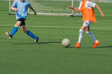 Fototapeta premium Children's football. An interesting football moment at the match and training. The active struggle and dynamics of the boys' soccer match. The boys are recklessly fighting for the ball
