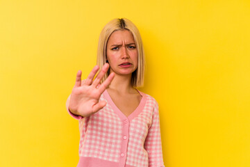 Young venezuelan woman isolated on yellow background rejecting someone showing a gesture of disgust.