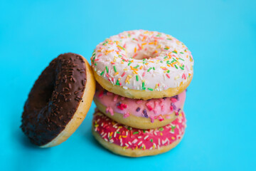 Air doughnuts are stacked on a blue background. The sweets are covered with chocolate and icing.