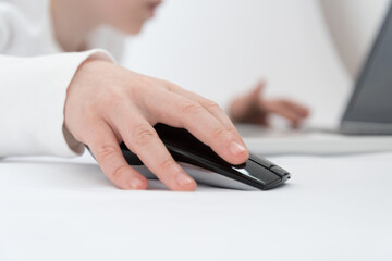 Children's hand close up. The child is engaged or plays in the laptop using a wireless mouse