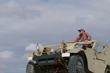 a man in a baseball cap and dark glasses in an old military vehicle
