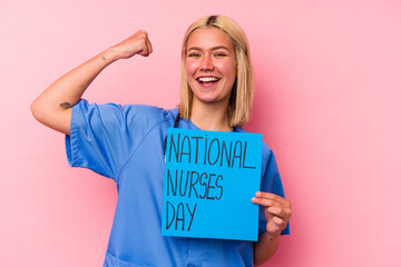 Young nurse woman holding a international nurses woman banner isolated on pink background