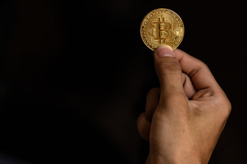 Close up one golden coin with the bitcoin symbol in hand. Young hand holding cryptocurrency coin, Money coins digital, BTC