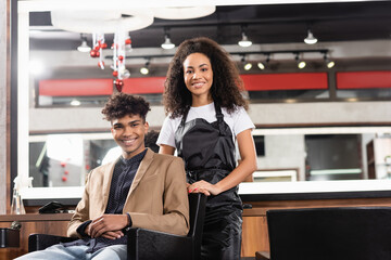 African american hairdresser and client smiling at camera in salon