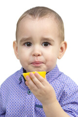 Preschool boy eating sour lemon, isolated white background.