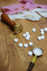 Vintage wax seal stamp lies on a wooden table. Golden spoon and pieces of wax