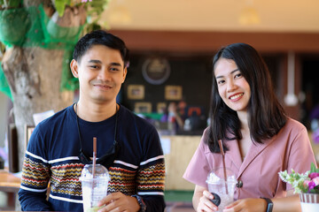 Asian couple sitting in the coffee cafe in the weeken. A couple relaxing in a cafe. Young asian couple drink coffee.