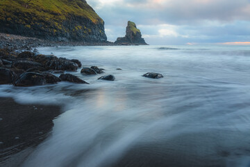 Moody seascape scenery and sea stack during sunrise or sunset at Talisker Bay Beach on the Isle of Skye, Scotland