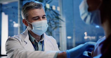 Adult doctor labortory clinician doing vaccination treatment procedure for young caucasian woman against covid-19 infection. Concept for healthcare.