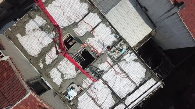 Aerial view of the building construction at the city center. Workers are pouring concrete to the floor. 
