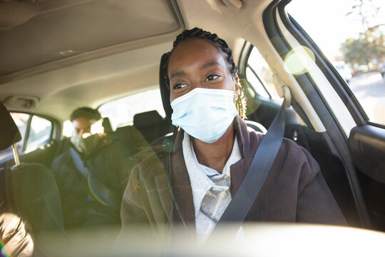 Portrait woman in face mask driving passengers in crowdsourced taxi