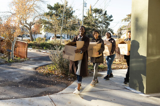 Teenage Volunteers Carrying Donation Boxes On Sunny Sidewalk