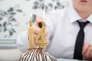 Teen lights candles on a cake on his 14th birthday