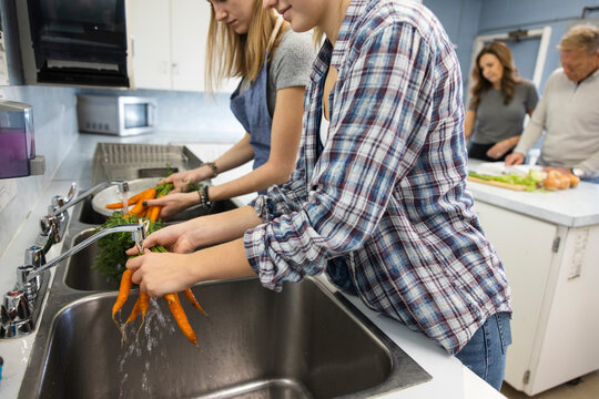 Family volunteers washing carrots at sink in soup kitchen
