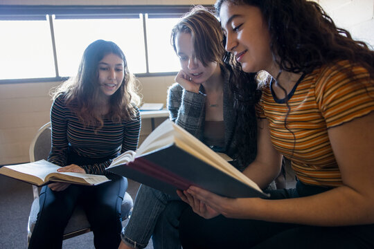 Teen girl friends reading in book club meeting