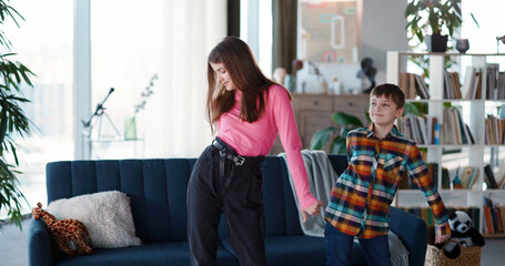 Couple of adorable brother and sister kids dancing in living room for online broadcast video vlog having fun together. Young bloggers. Vlogging lifestyle.