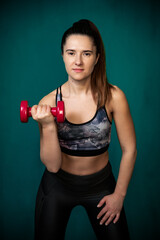 Girl performs exercises using dumbbells.