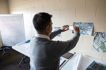 Man photographing urban planning maps in community center