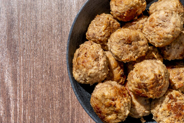 Minced meat ball in black plate, selective focus. Homemade cutlets on a wooden background in rustic style with copy space. Top view, flat lay