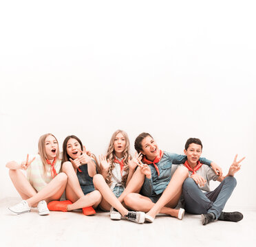 cute smiling tenagers sitting on the floor with legs crossed