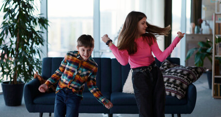 Couple of amazing teenage kids sister and brother dancing in living room into music enjoying entertainment vlogging online for follower broadcast making video.