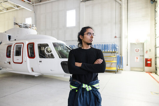 Man standing in front of helicopter in hangar