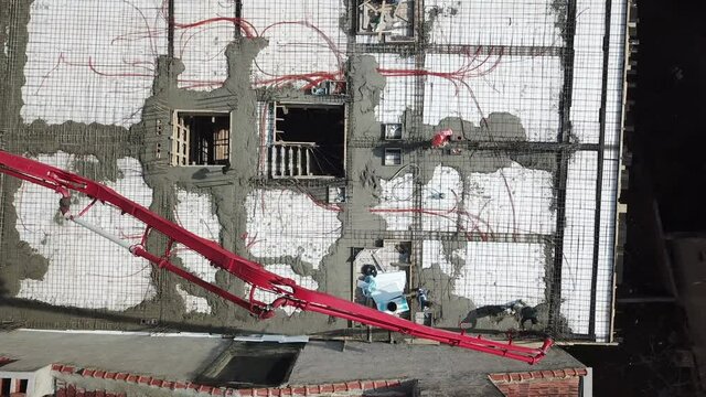 Aerial view of the building construction at the city center. Workers are pouring concrete to the floor. 