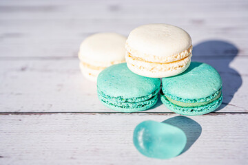 Selective focus. Turquoise and white macarons on light wooden background. French Pastel Macaroons. Blurred focus