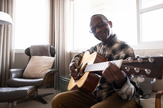 Portrait of senior man playing guitar at home