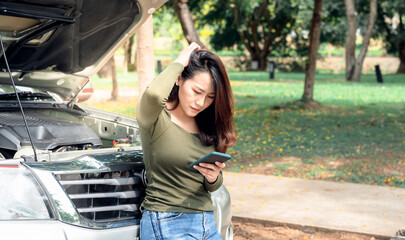 Asian attractive woman using a mobile phone To ask for help, because her pickup truck was broken,...