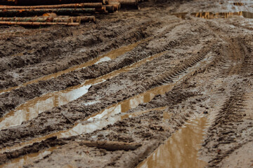 mud on the muddy road. tracks from the wheels of passing cars in the wet, softened ground. the road is difficult for transport to pass. puddles in the pits of a country dirt road
